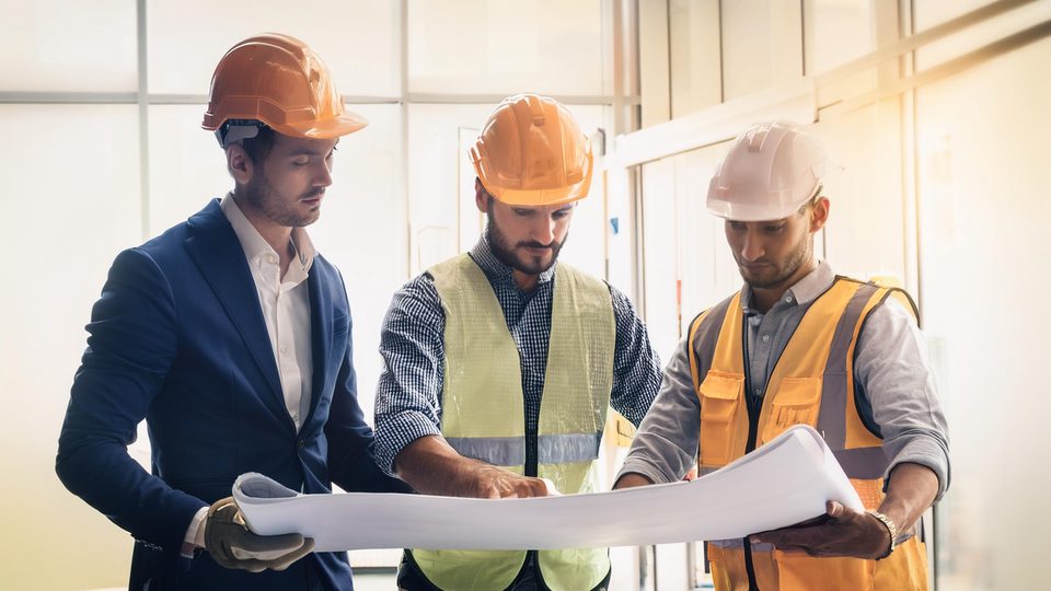Bauleiter und Handwerker besprechen den Plan